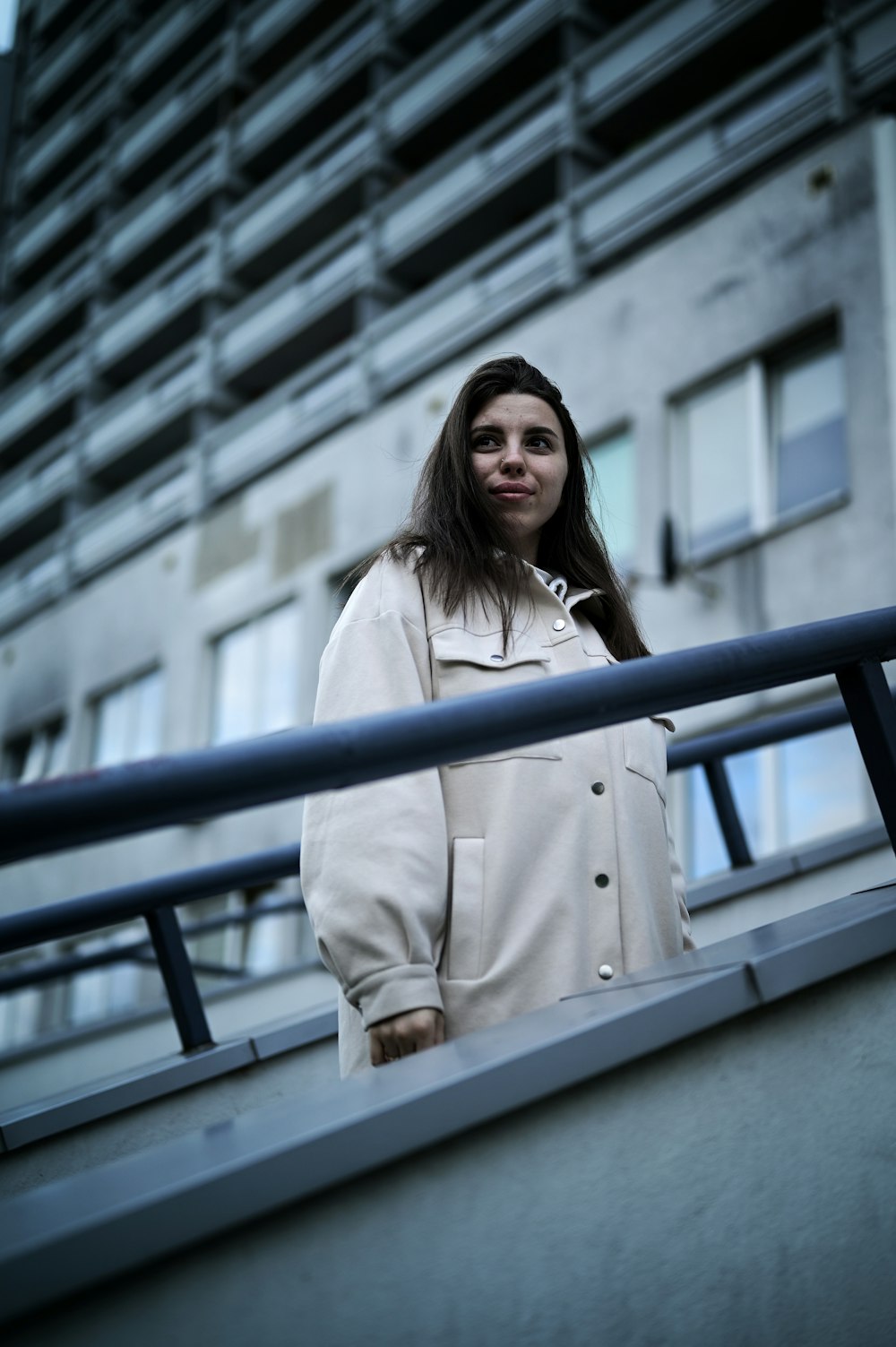 a woman standing on a balcony in front of a building