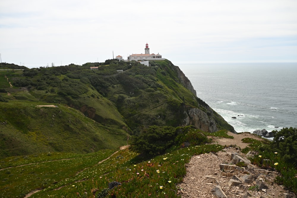 a path leading to a lighthouse on a cliff by the ocean