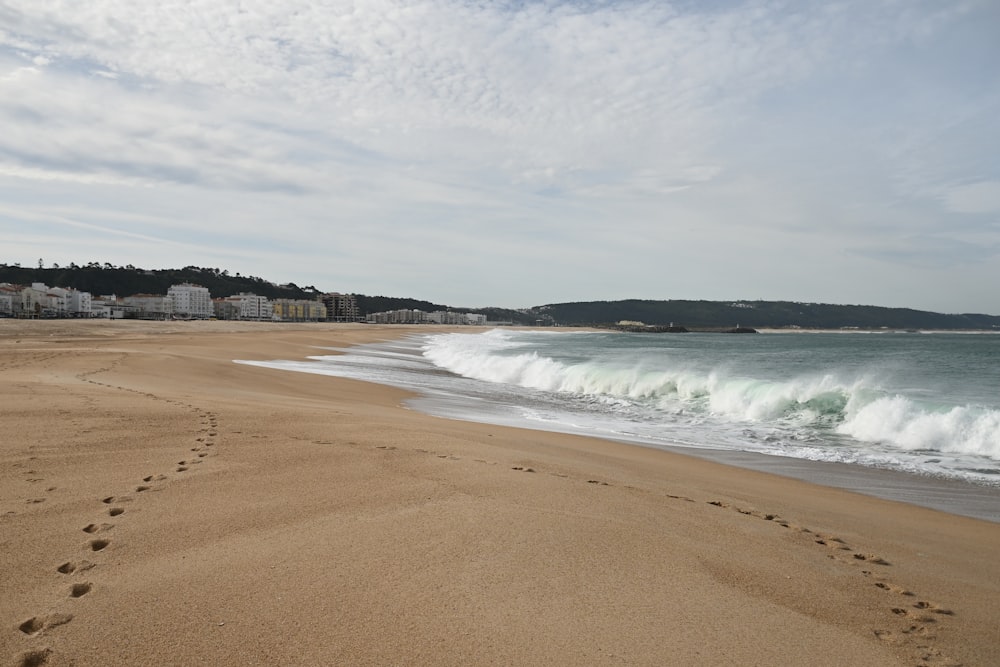 a sandy beach with a wave coming in to shore