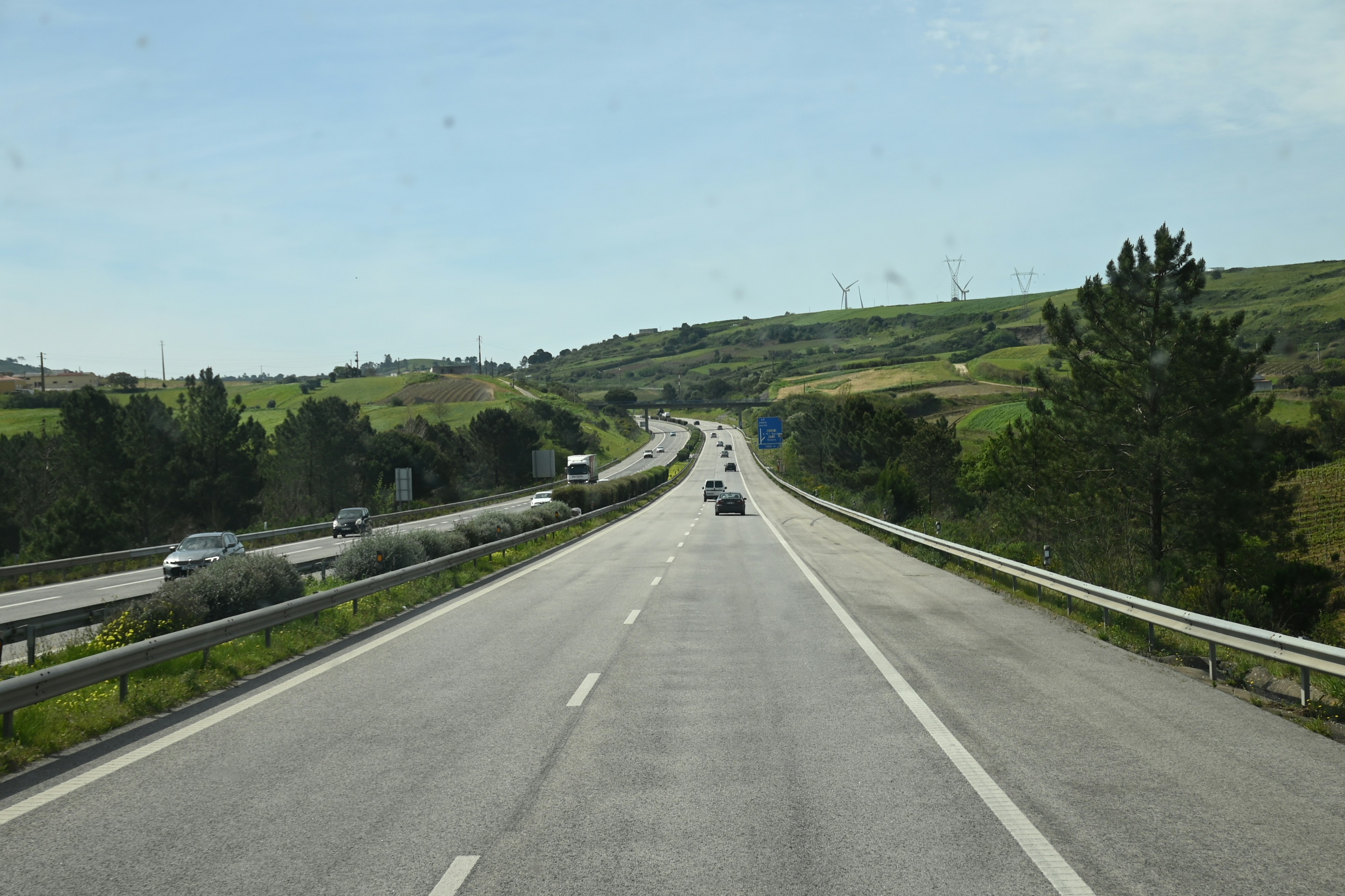 a car driving down a highway next to a lush green hillside