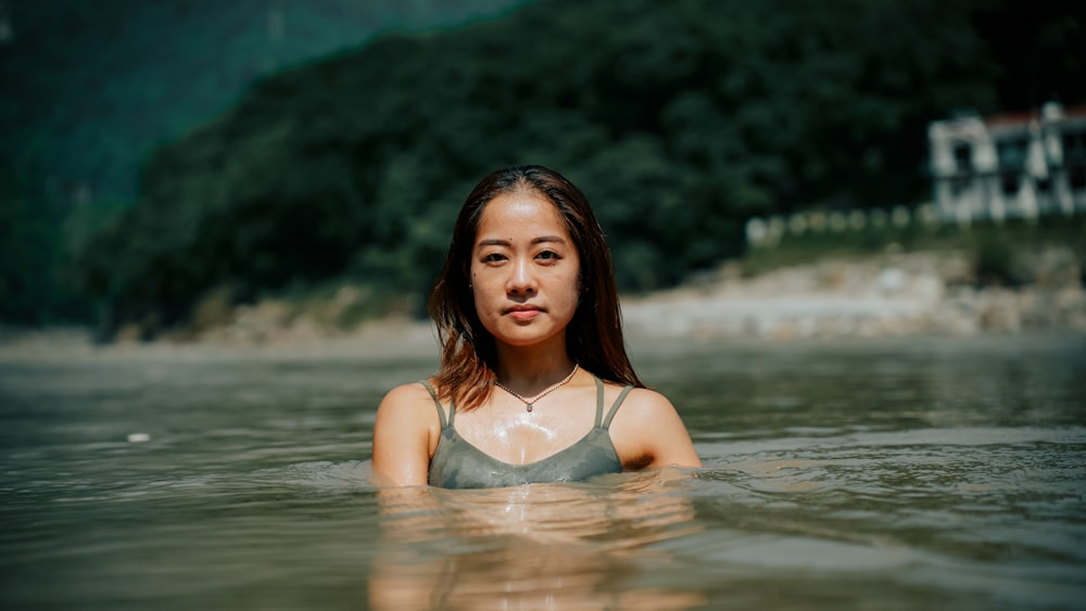 a woman in a body of water with a house in the background