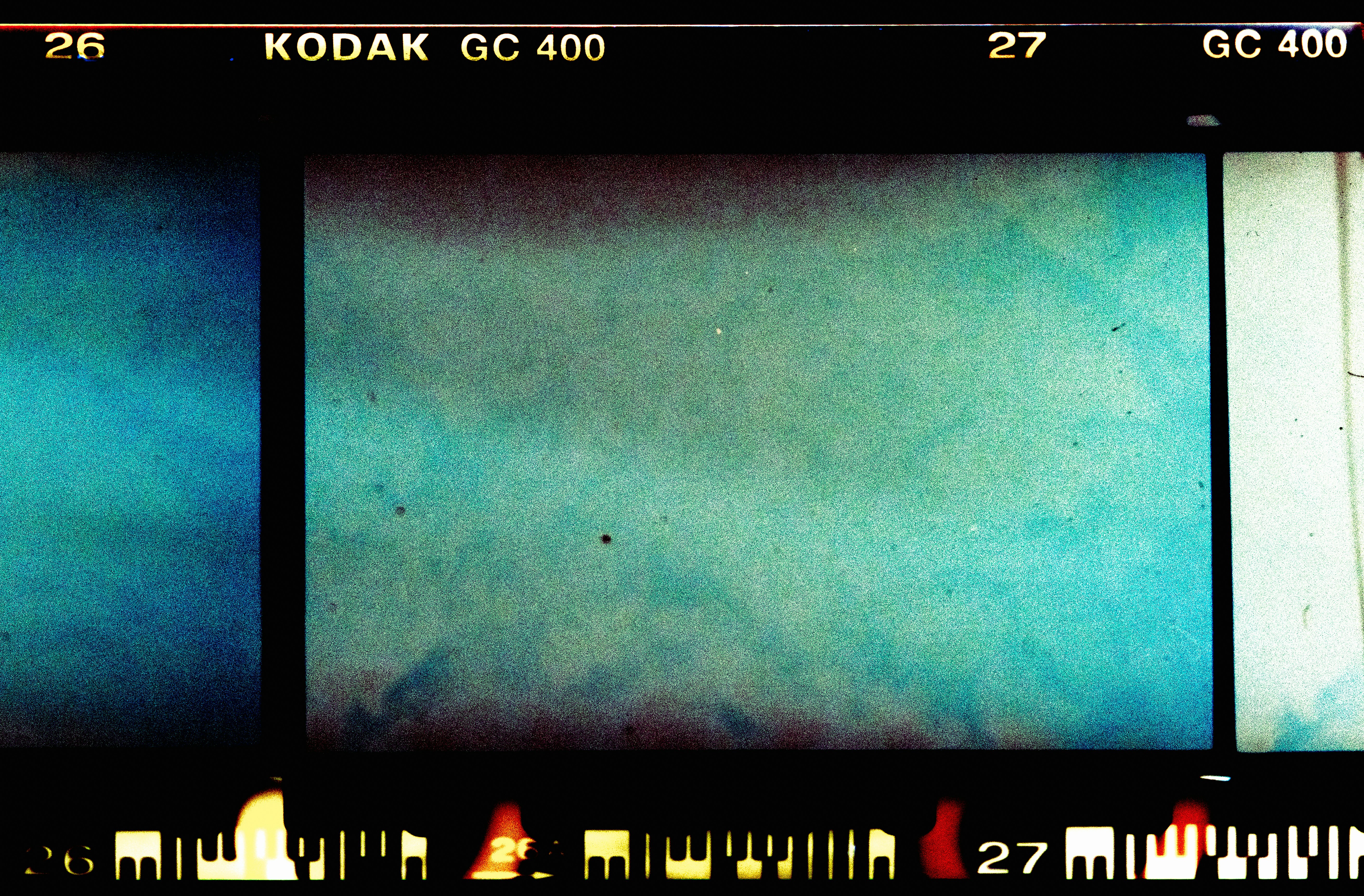 A medium-wide shot of a folding table in a community room with several neatly sorted piles of new, unwrapped children's gifts—board games, stuffed animals, picture books—alongside rolls of colorful wrapping paper and ribbon. Two volunteers in casual winter sweaters are mid-task sorting items into labeled cardboard boxes. Natural overhead fluorescent mixed with window light, documentary photography style, moderate depth of field. No visible text, signage, logos, or on-screen graphics; no celebrity likenesses; no stock-photo clichés.