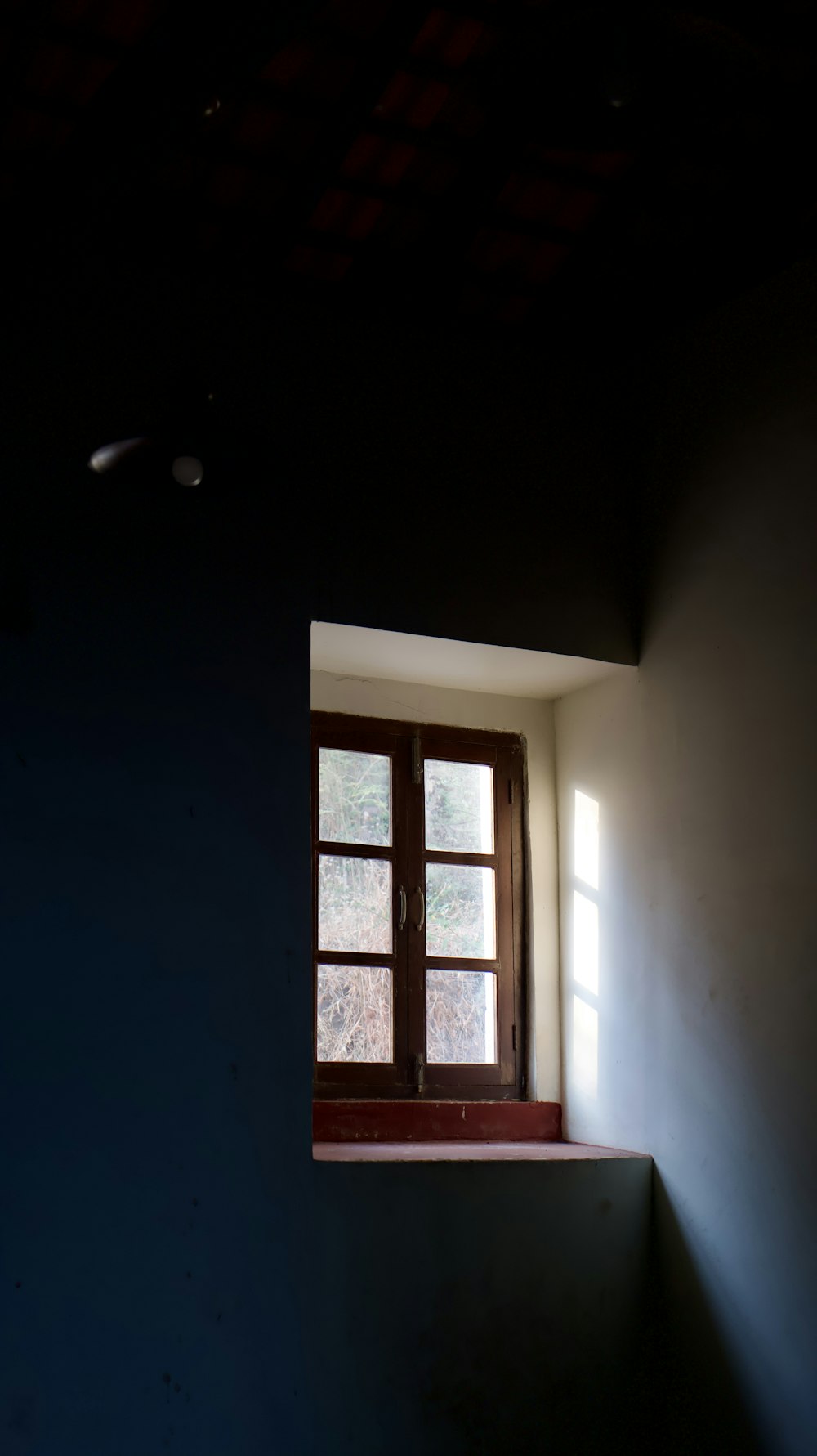 a dark room with a window and a light coming in