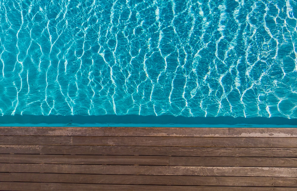 an overhead view of a swimming pool with a wooden deck