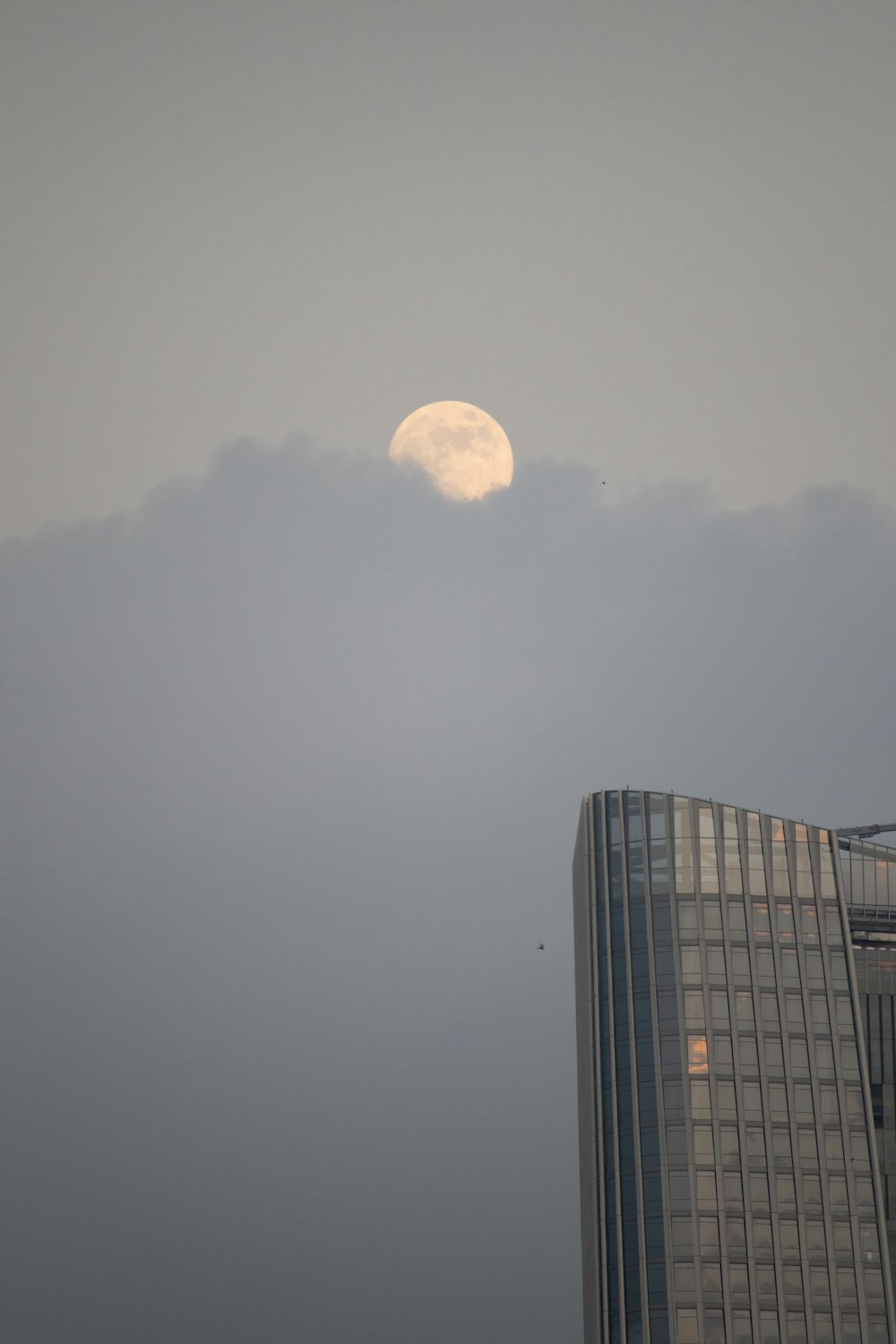 a very tall building with a very large moon in the sky