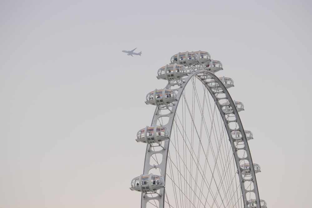 a ferris wheel with a plane flying in the background