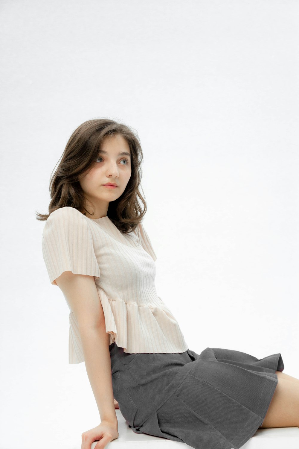 a woman is sitting on a white surface