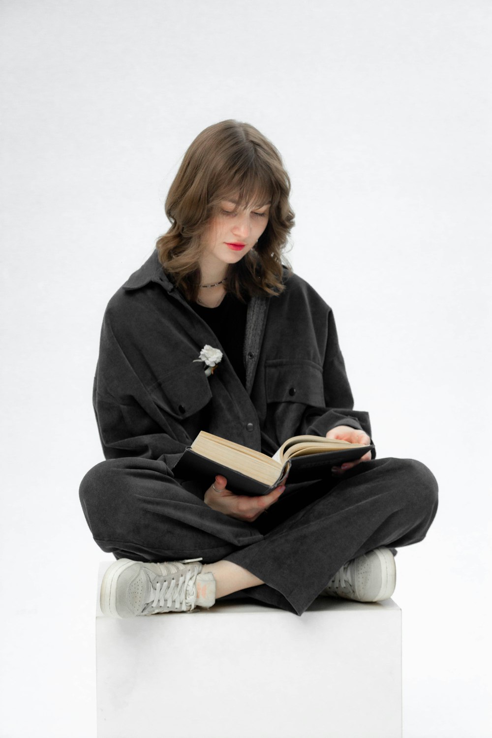 a woman sitting on a cube reading a book