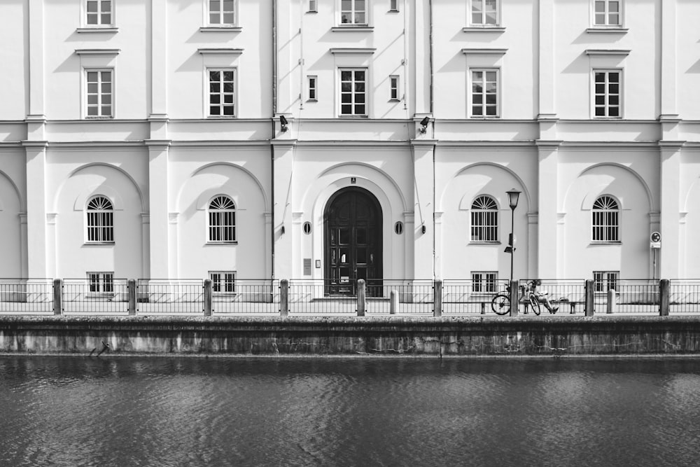 a black and white photo of a building next to a body of water