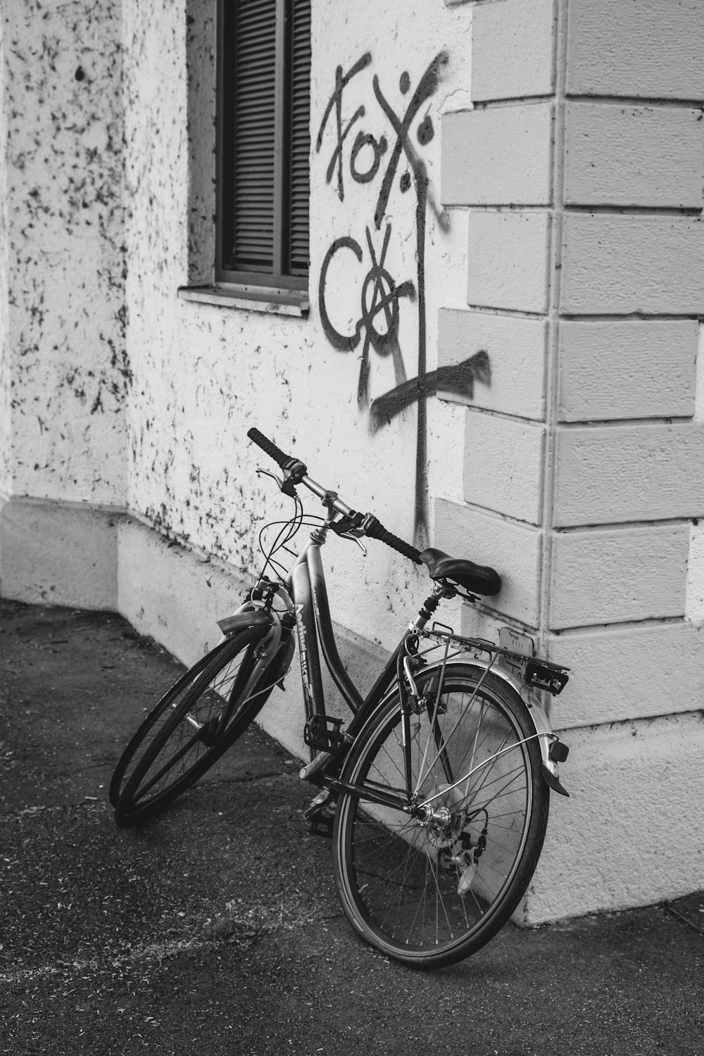 a bicycle parked next to a building with graffiti on it