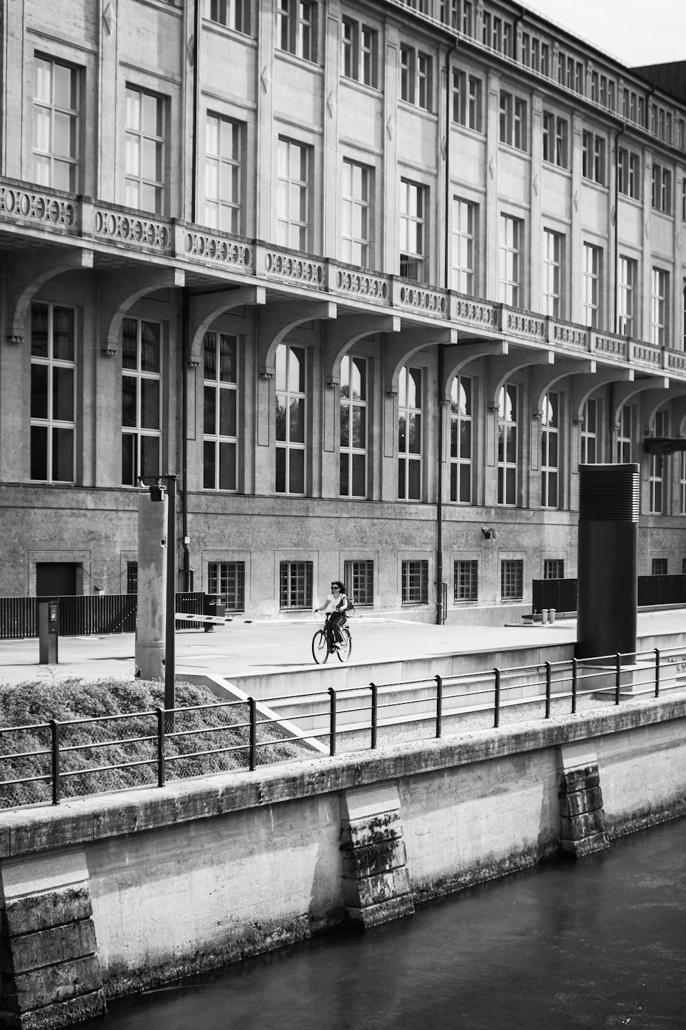 a black and white photo of a person walking by a building