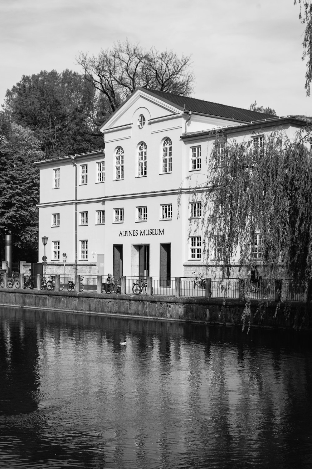a black and white photo of a building next to a body of water