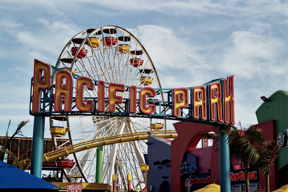 a sign that says pacific park with a ferris wheel in the background