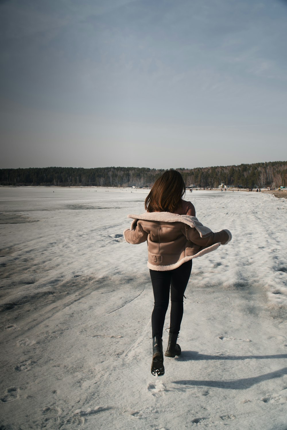 a woman walking across a snow covered field