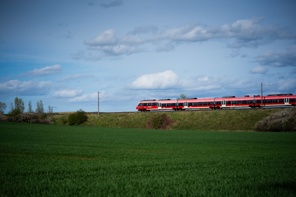 a red train traveling through a lush green field