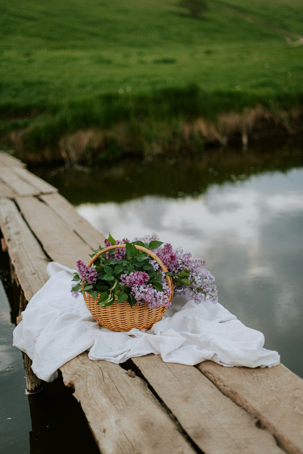 a basket of flowers sitting on a wooden dock