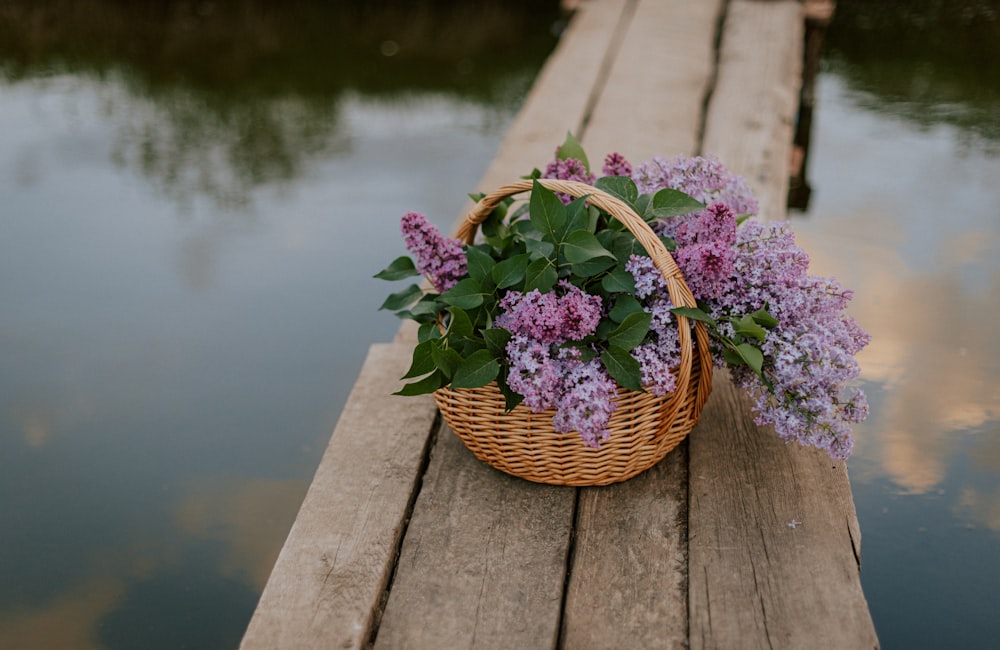 una canasta de lilas sentada en un muelle de madera