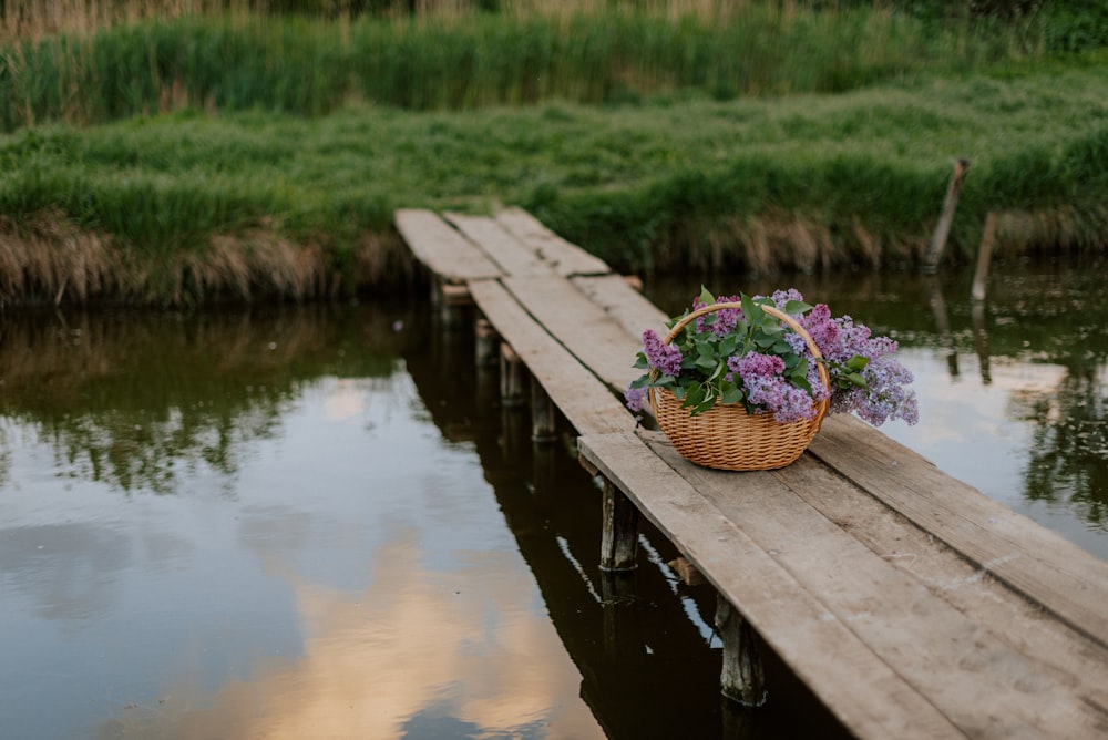 a basket of flowers sitting on a wooden dock