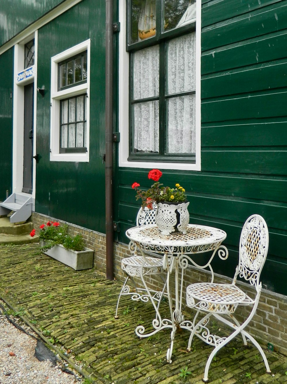 a white table and chairs sitting outside of a green house