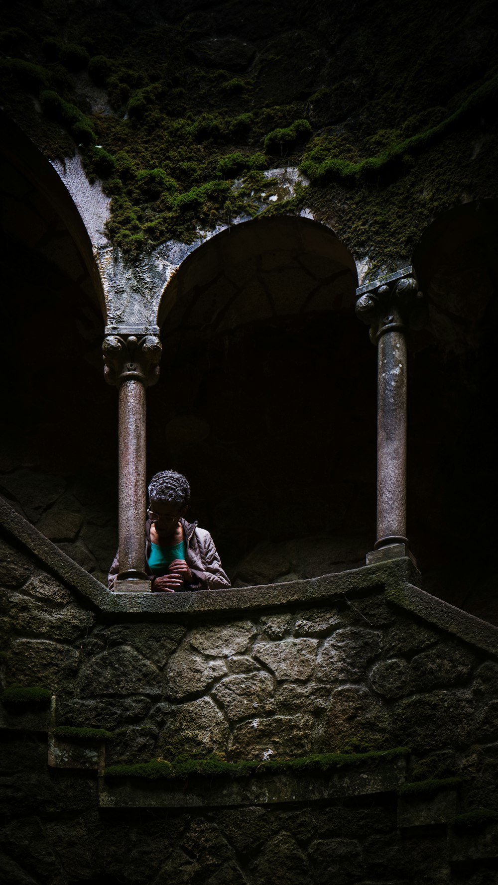 a woman sitting on a stone wall with her head in her hands
