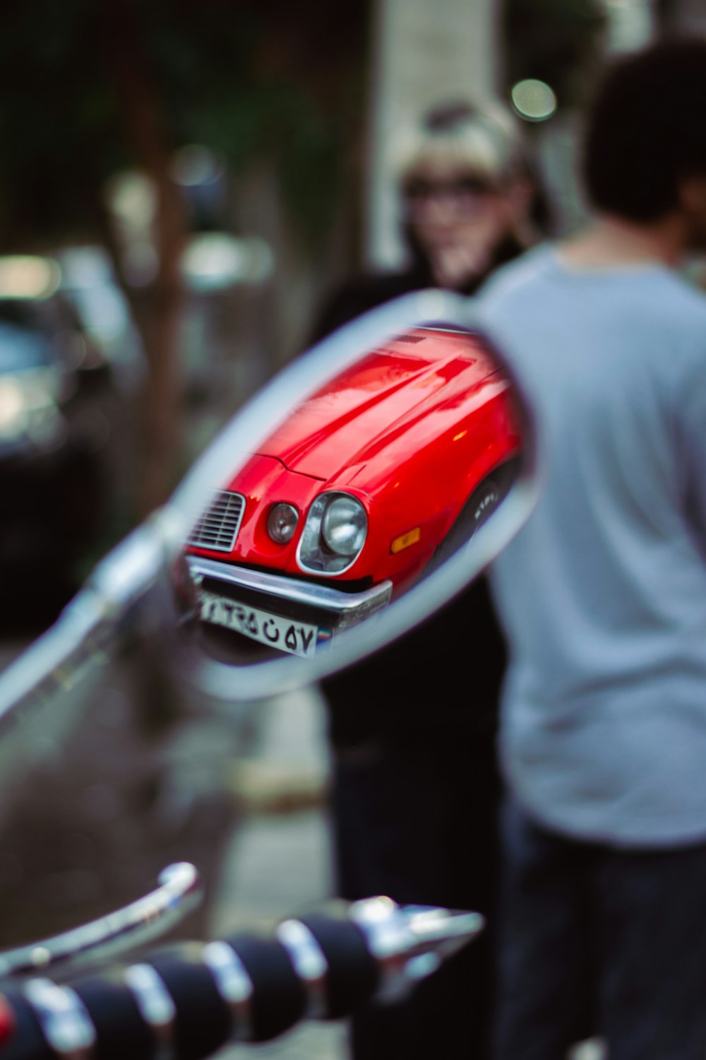 a red car is seen through a mirror