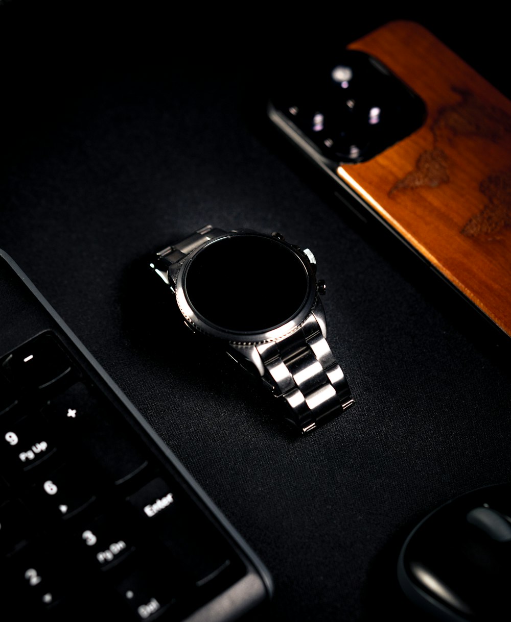 a watch sitting on top of a desk next to a keyboard