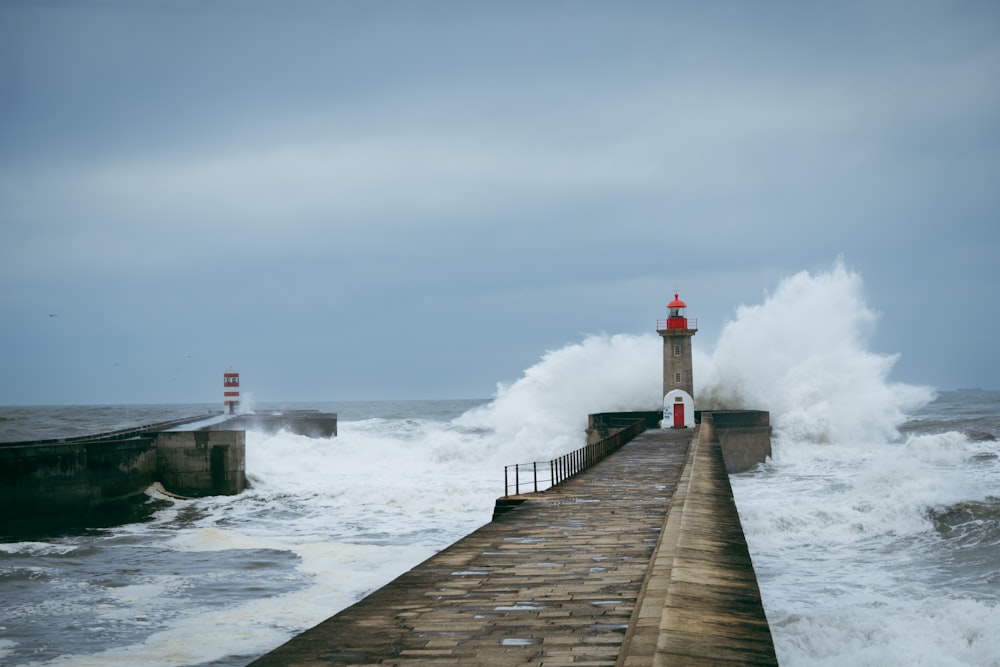 a lighthouse on a pier surrounded by waves