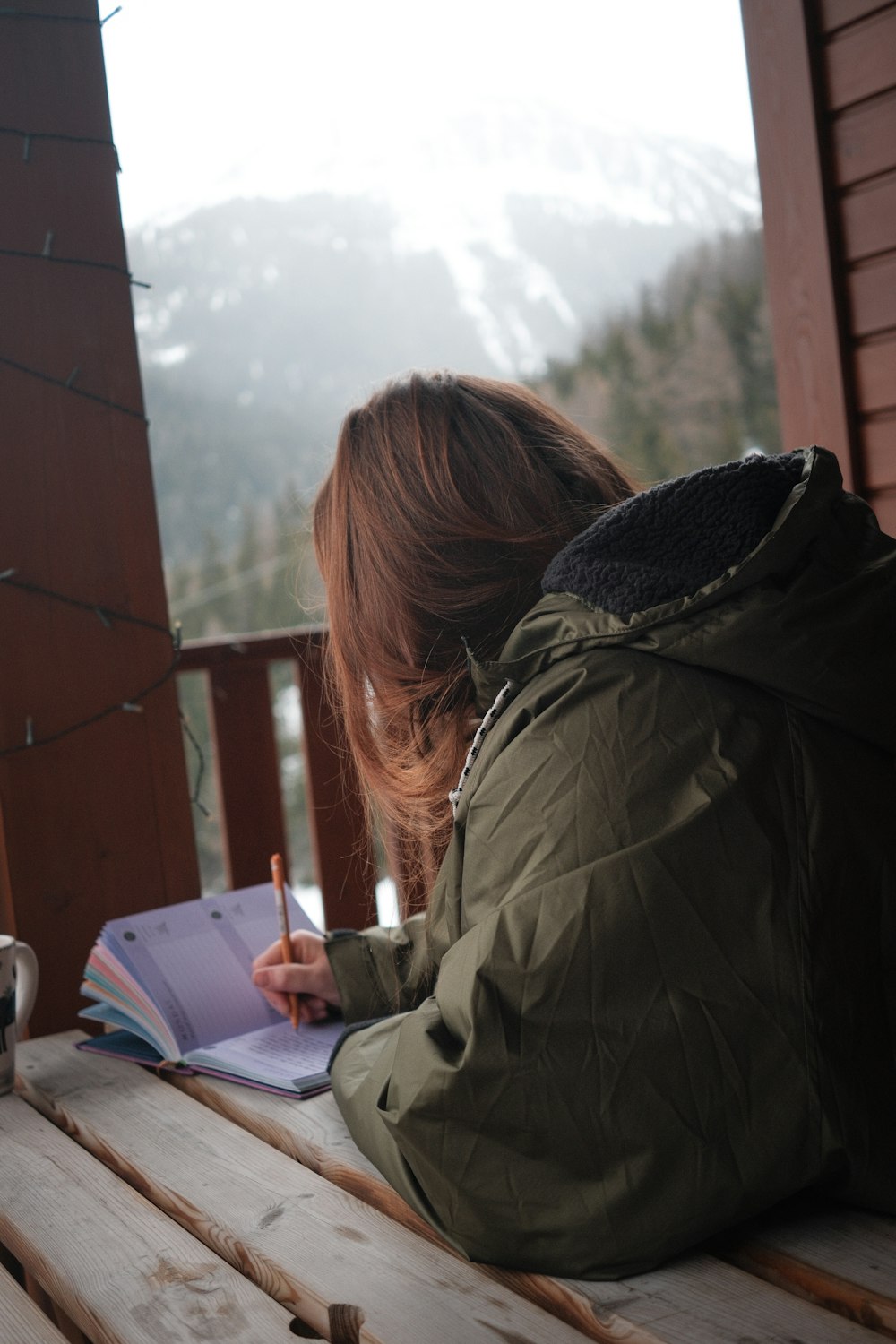 a woman sitting on a bench writing on a notebook