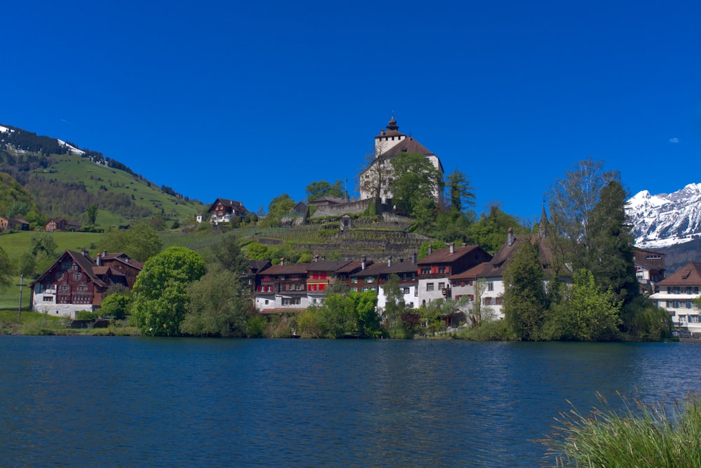 a lake with houses on the side and a mountain in the background