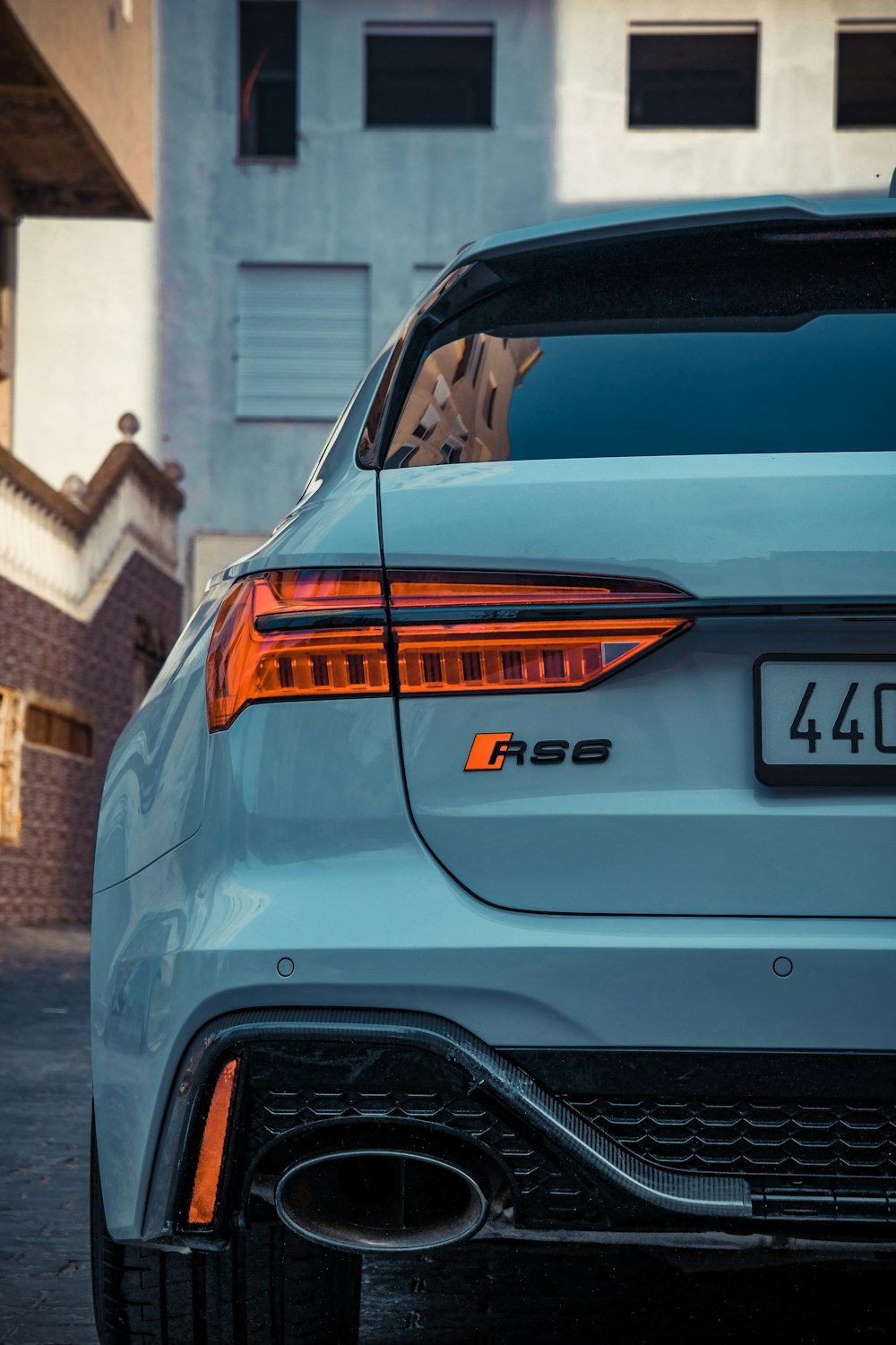 the rear end of a white car parked in front of a building