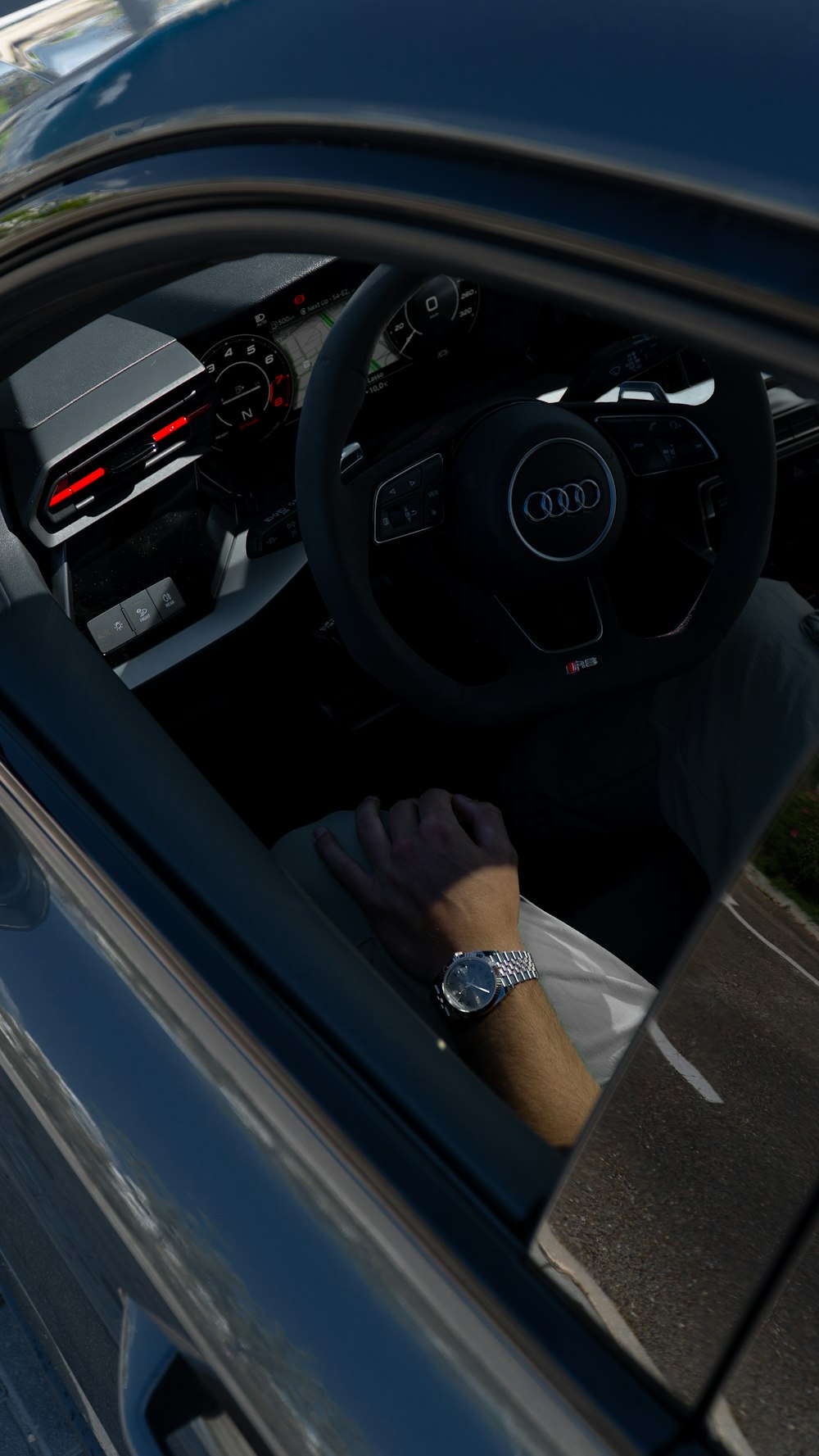 a person sitting in a car with their hand on the steering wheel