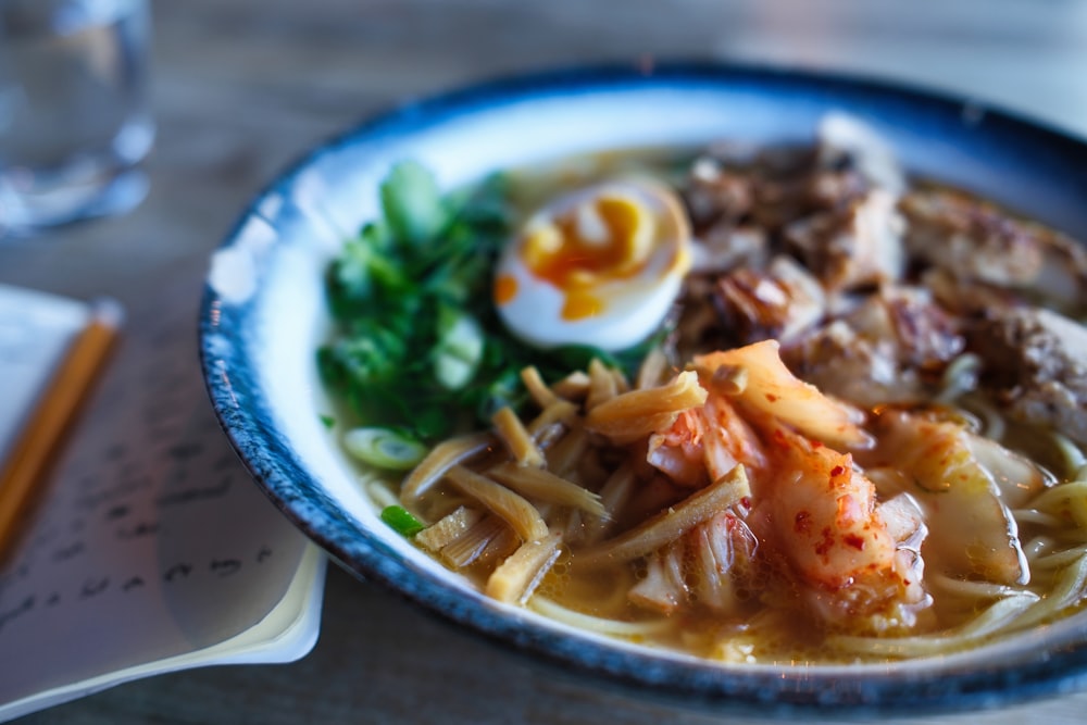 a blue and white bowl filled with noodles and meat