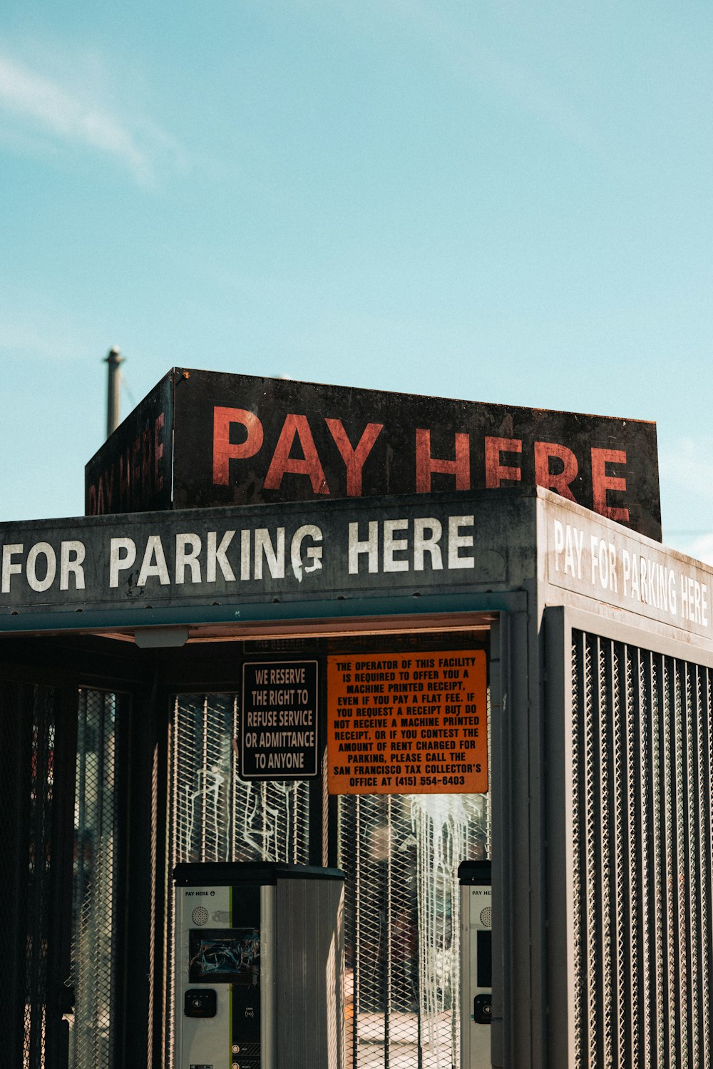 a pay here for parking here sign on a building