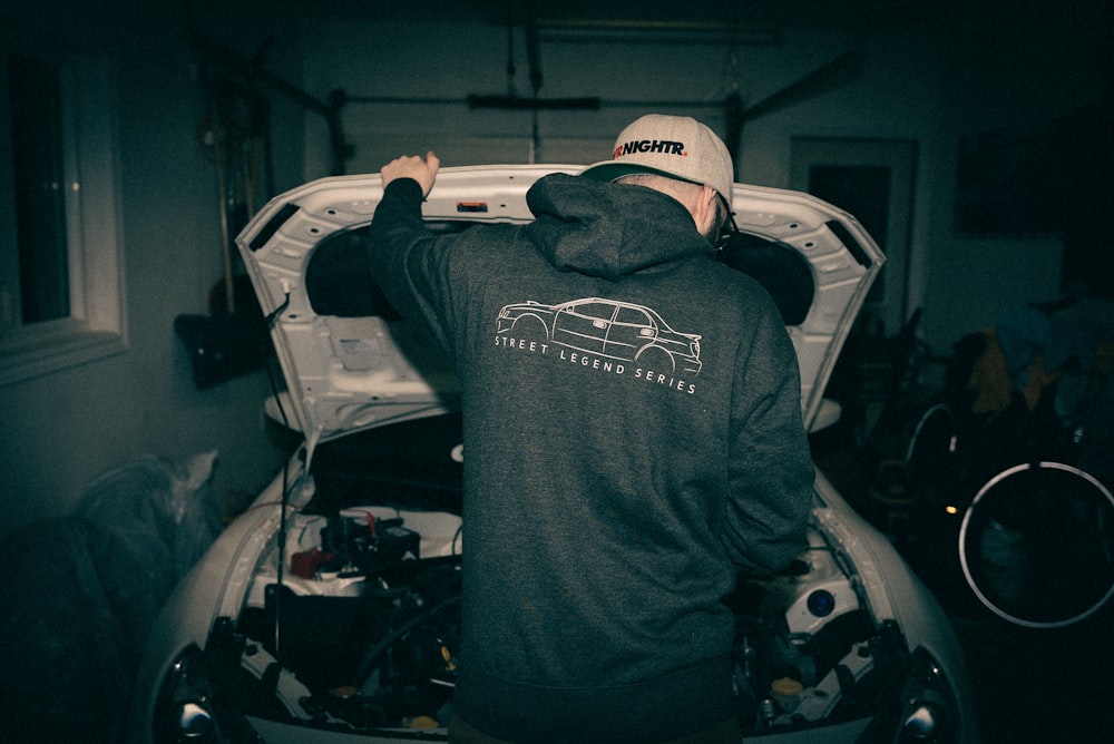 a man standing next to a car in a garage