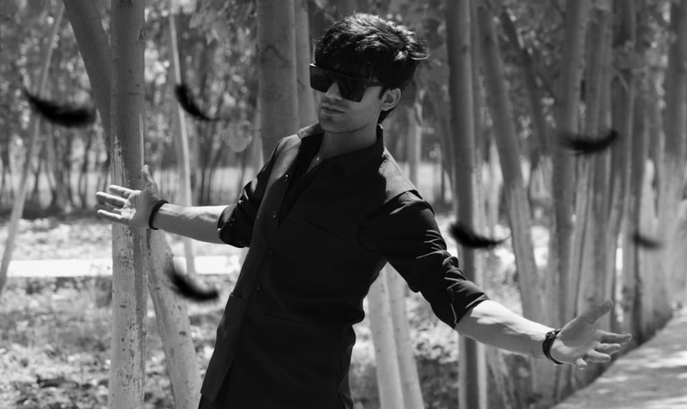 a man wearing sunglasses standing in front of a bamboo tree