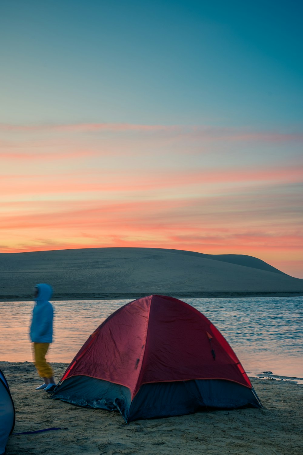 una persona in piedi accanto a una tenda rossa e blu
