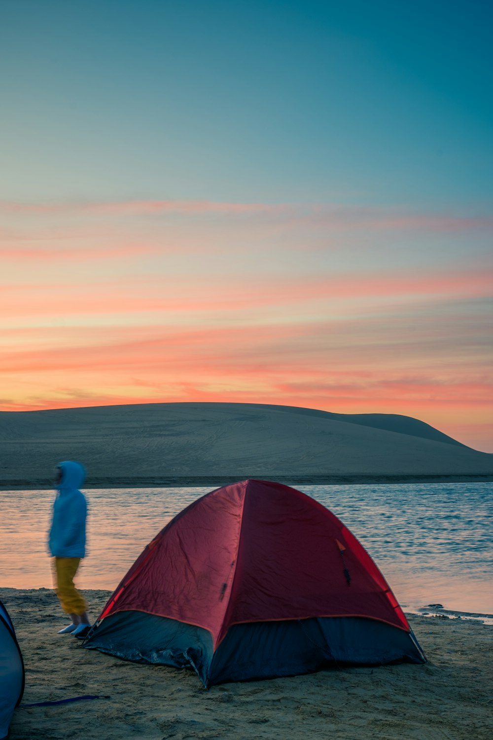 a person standing next to a red and blue tent