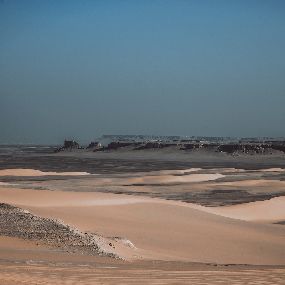 a desert landscape with sand dunes and a building in the distance