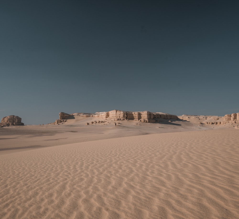 a sandy area with a few rocks in the distance