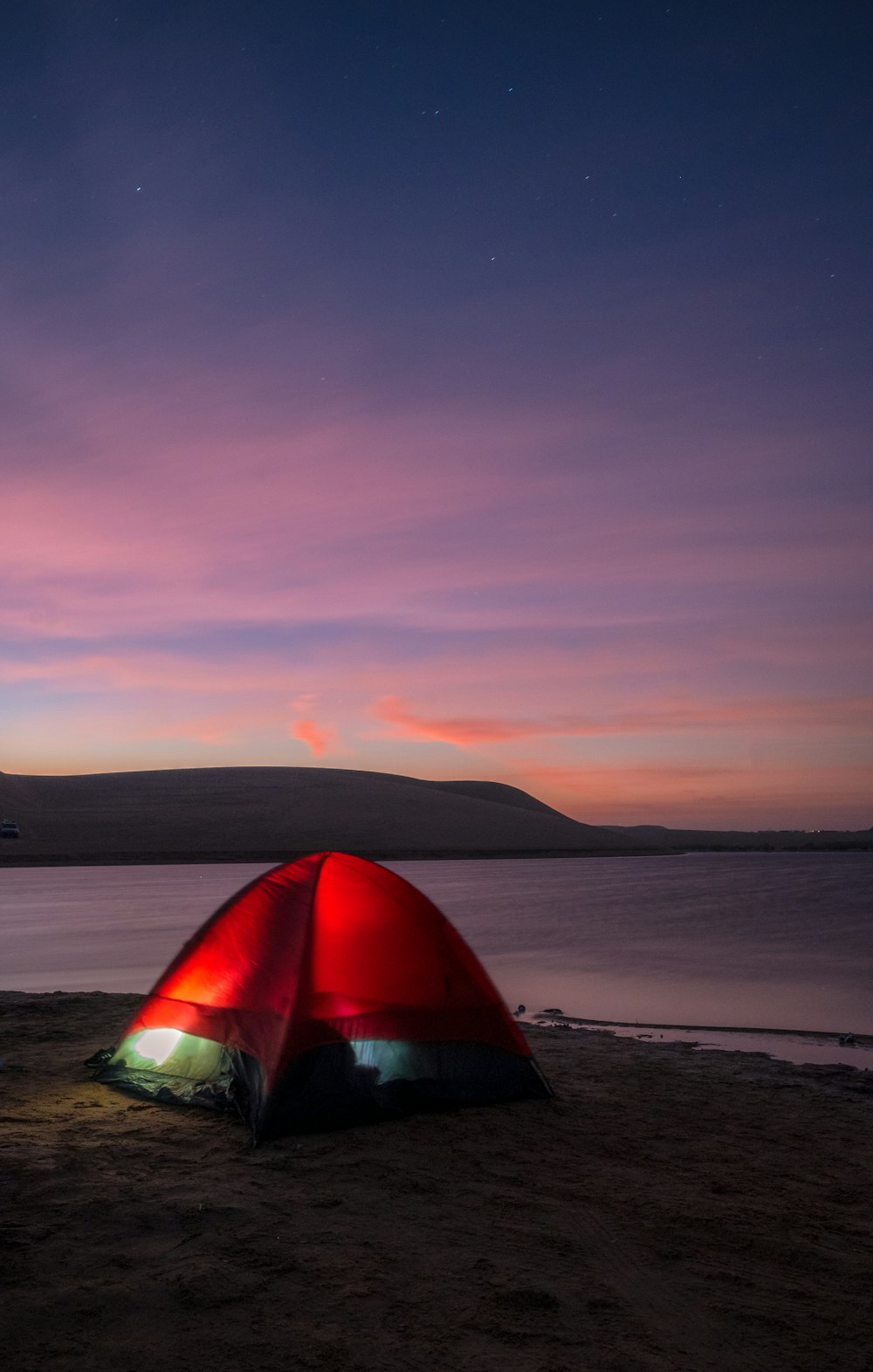 a red tent sitting on top of a sandy beach