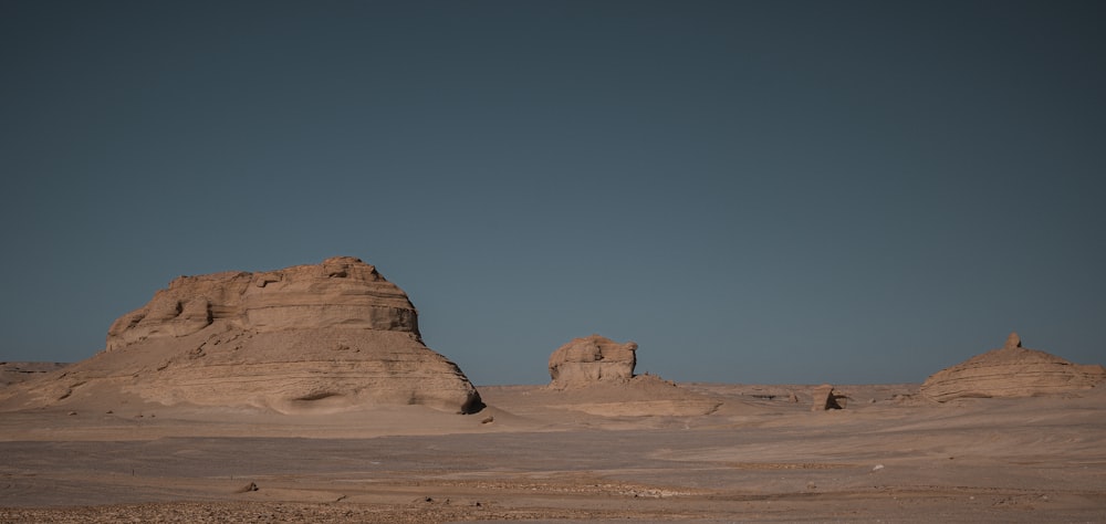 a desert landscape with a rock formation in the distance