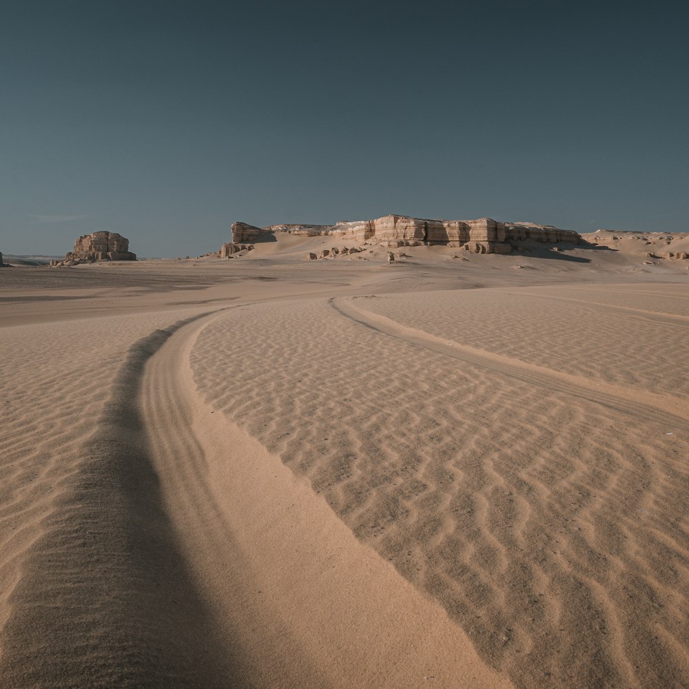 a large sandy area with some rocks in the background