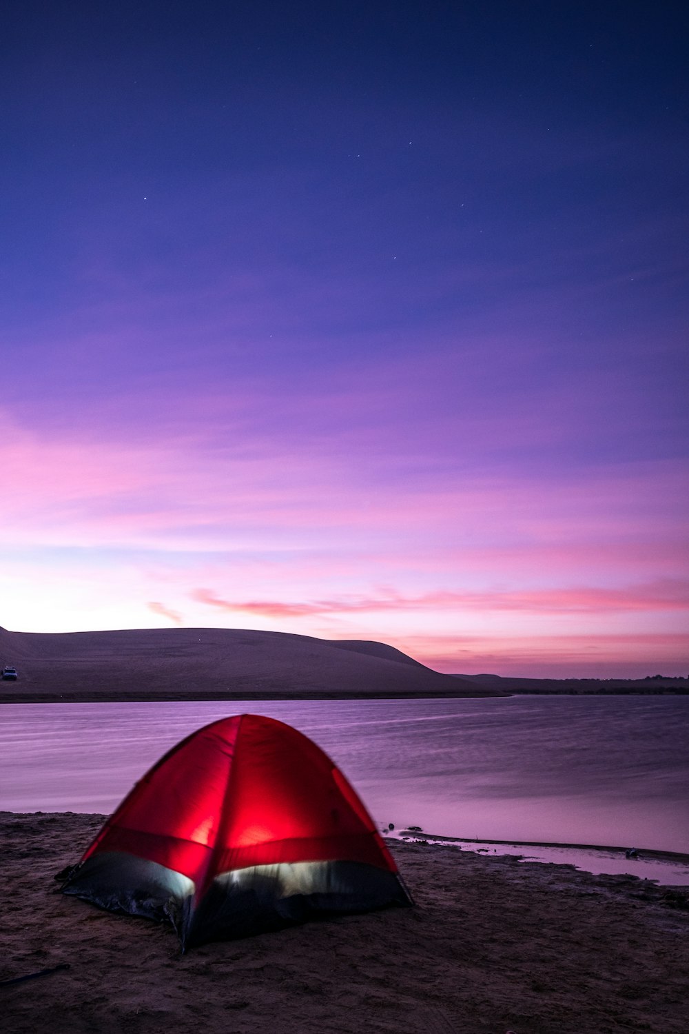 a red tent sitting on top of a sandy beach