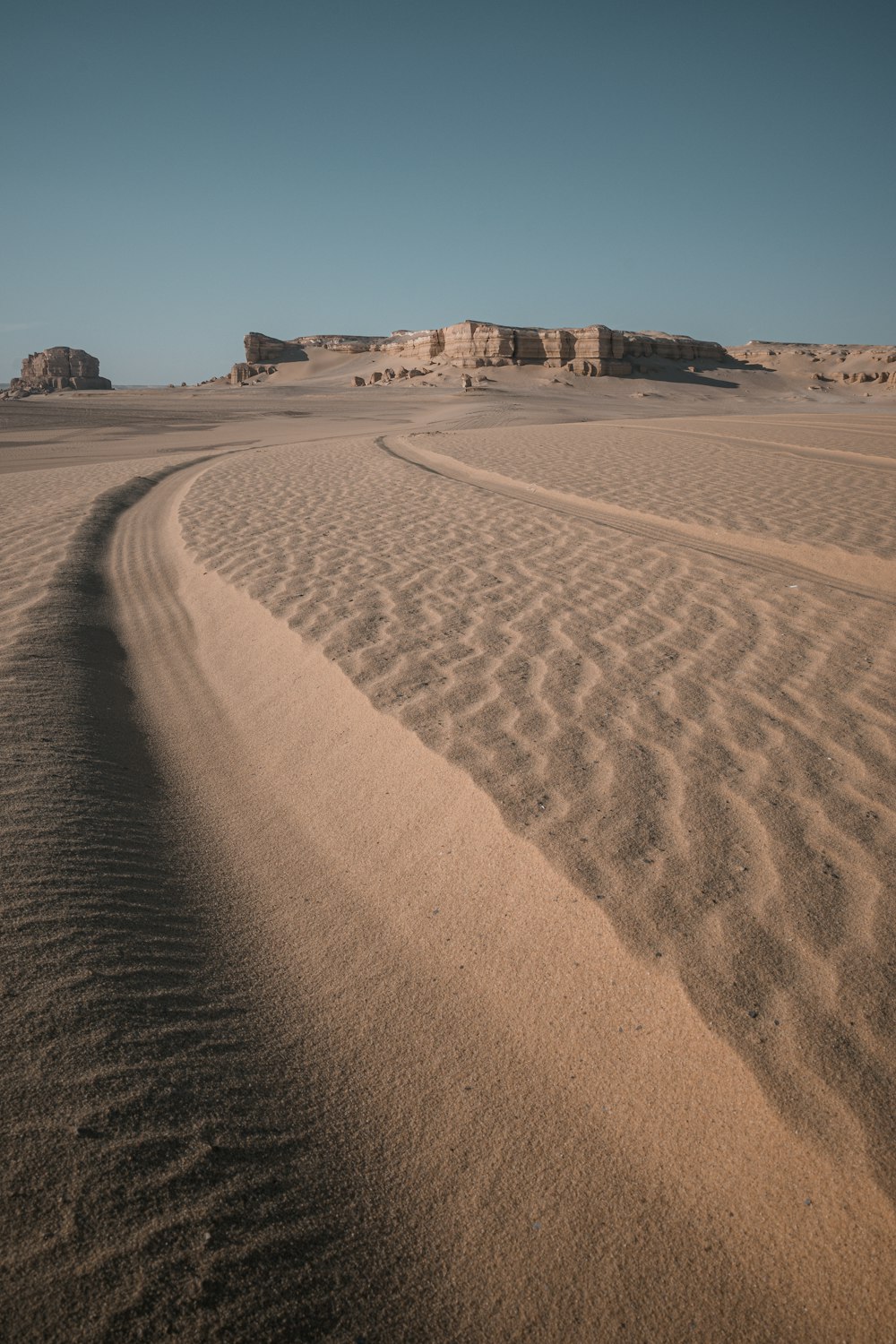 a sandy area with a few rocks in the distance