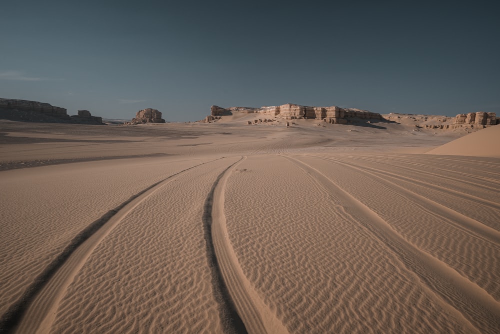 two tracks in the sand with a mountain in the background