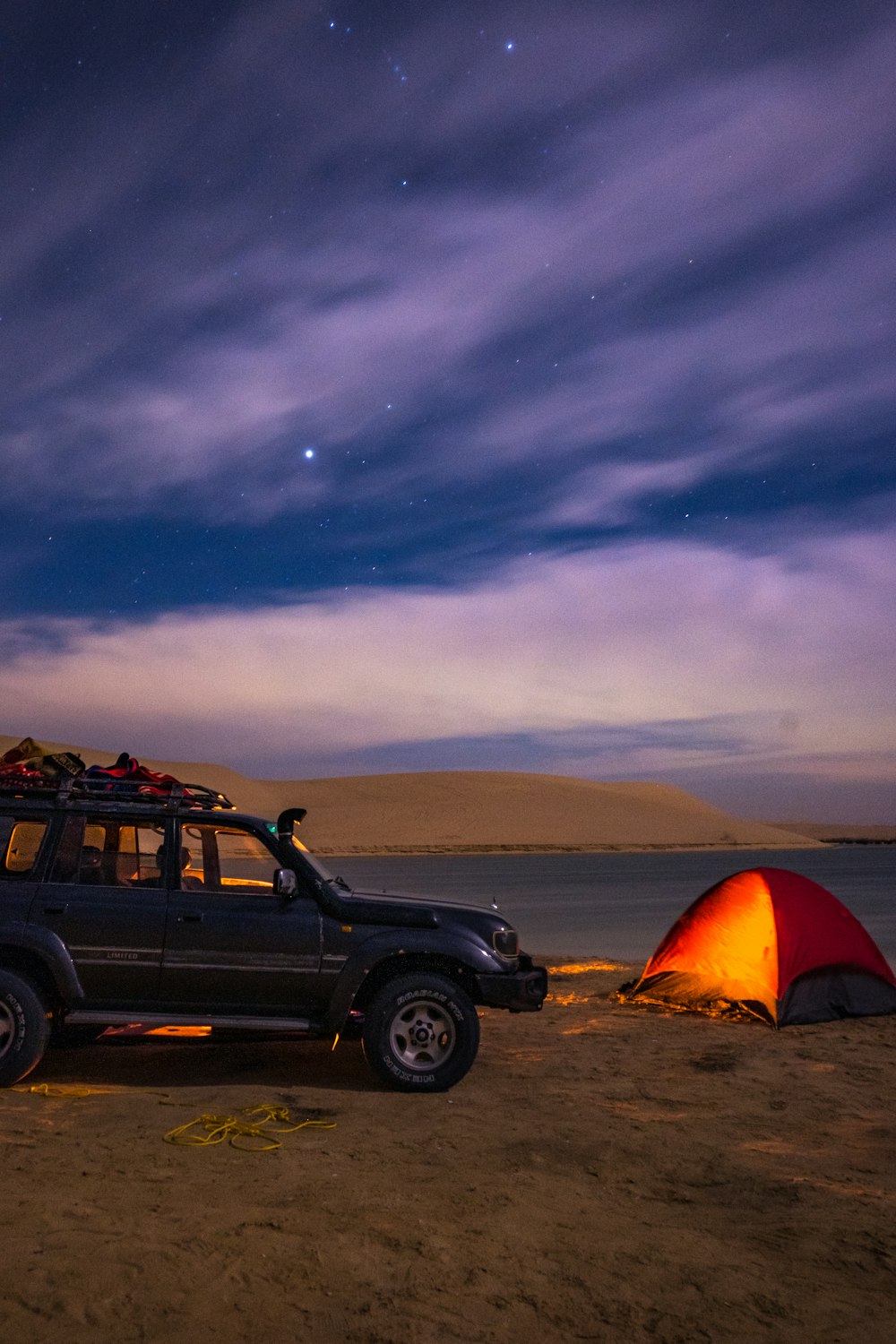 a car parked on a beach next to a tent