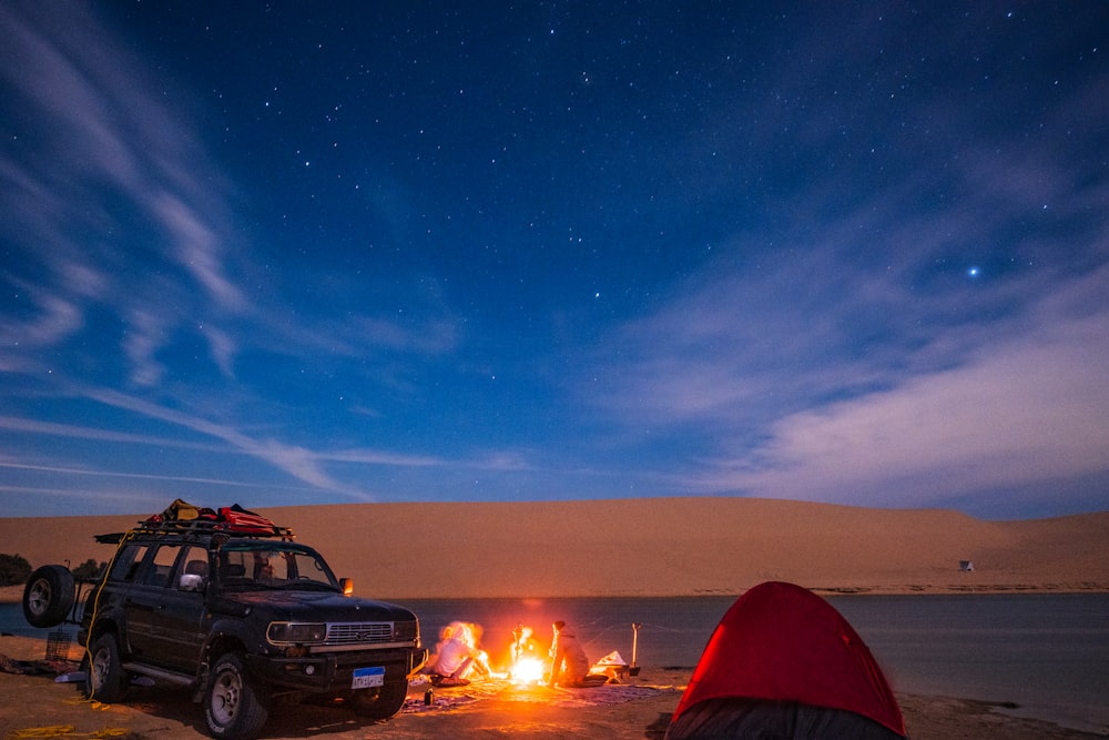 a car is parked next to a campfire in the desert