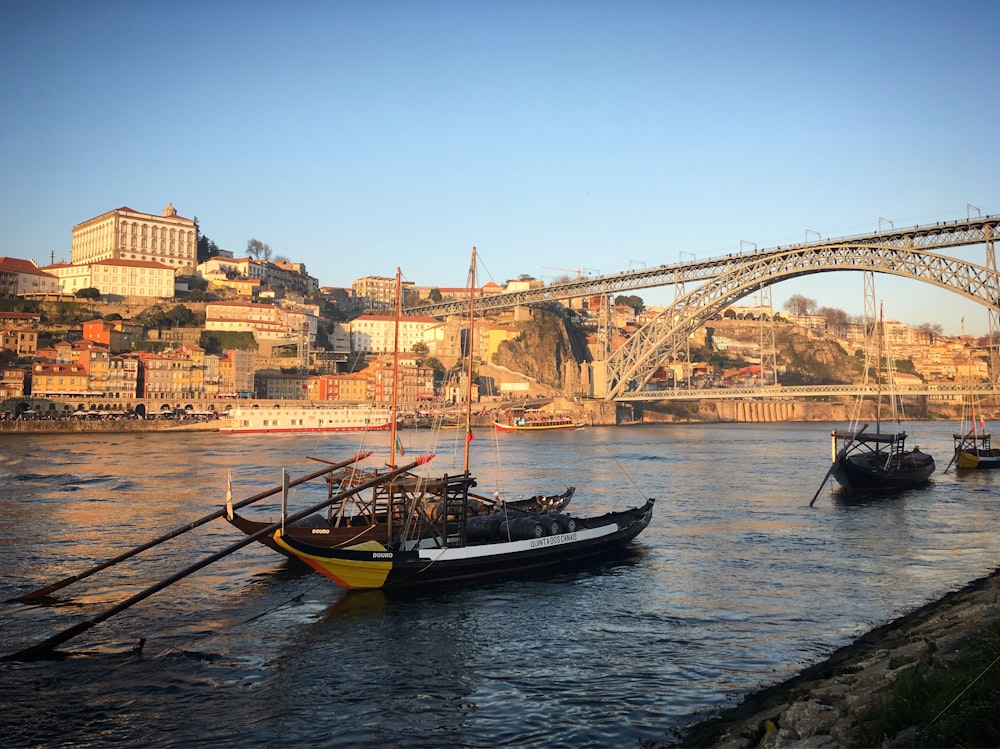 a group of boats floating on top of a river next to a bridge