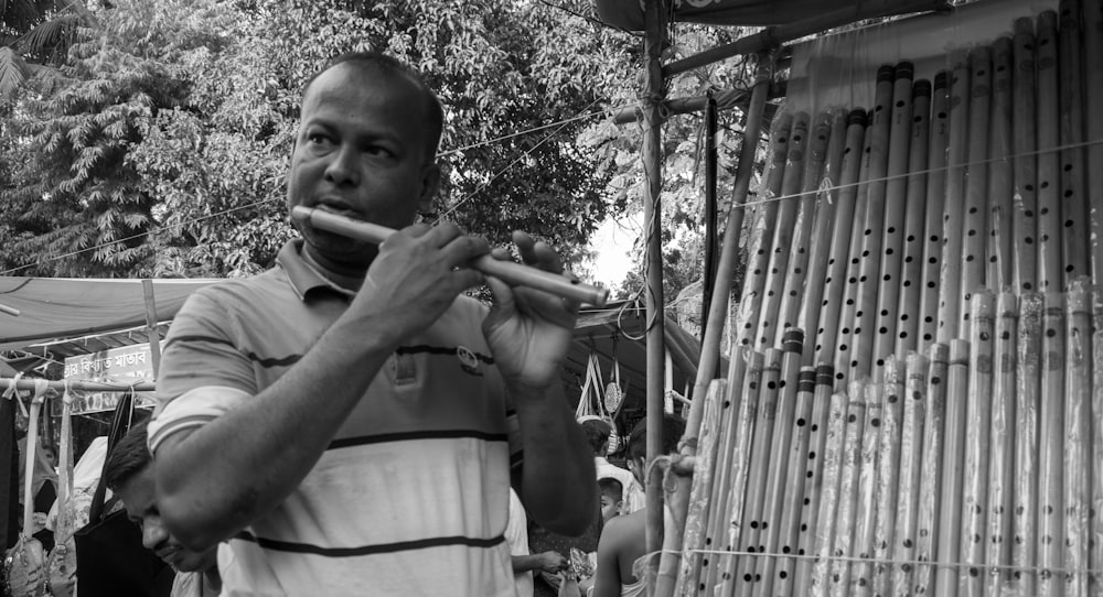 a man playing a flute in front of a bamboo hut