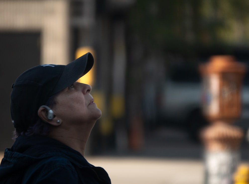 a woman in a black hat looking up at a yellow fire hydrant